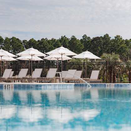 A pool with white umbrellas and chairs.