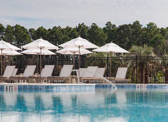A pool with white umbrellas and chairs.