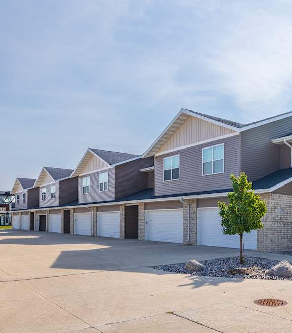 A large, modern house with a grey and brown exterior and a white garage door.