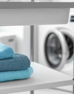 a stack of towels on a shelf in front of a washing machine