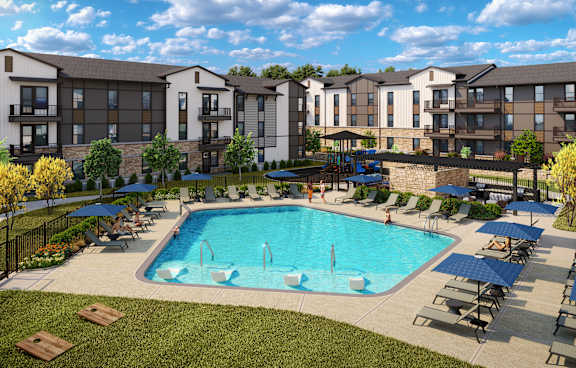 A large swimming pool surrounded by lounge chairs and umbrellas in front of apartment buildings.