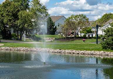A fountain in the middle of a lake surrounded by a stone wall.