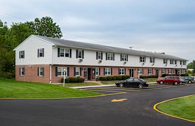 A black car is parked in a parking lot in front of a white building.