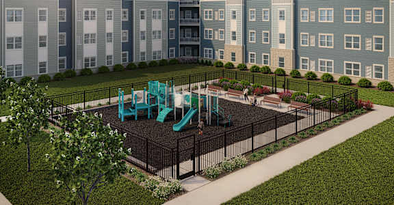 A playground with a green slide is surrounded by a black fence and a grassy area.