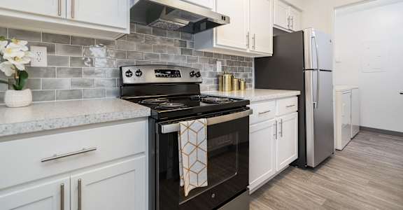 a kitchen with white cabinets and black appliances and a stainless steel refrigerator