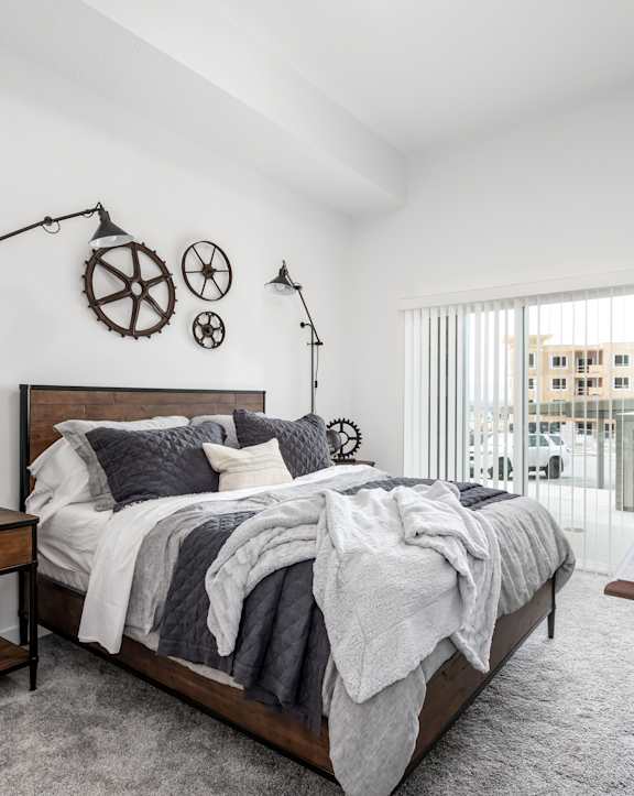 A bedroom with a large bed, a wooden table, and a window with a view of a building outside.