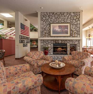 a living room with couches a table and a fireplace at Hilltop Commons Senior Living, Grass Valley