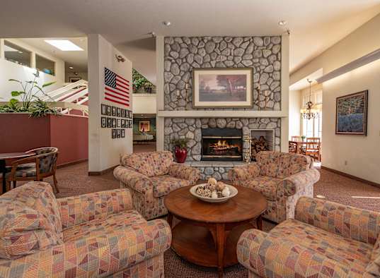 a living room with couches a table and a fireplace at Hilltop Commons Senior Living, Grass Valley