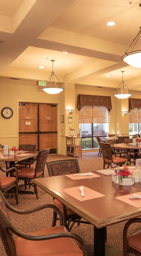 a large dining room with tables and chairs and windows  at Castle Vista Senior Duplex Community, Atwater, CA