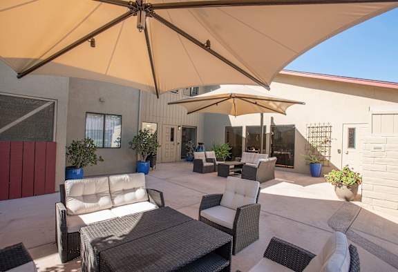 a patio with tables and chairs and umbrellas at Lodi Commons Senior Living, Lodi, CA
