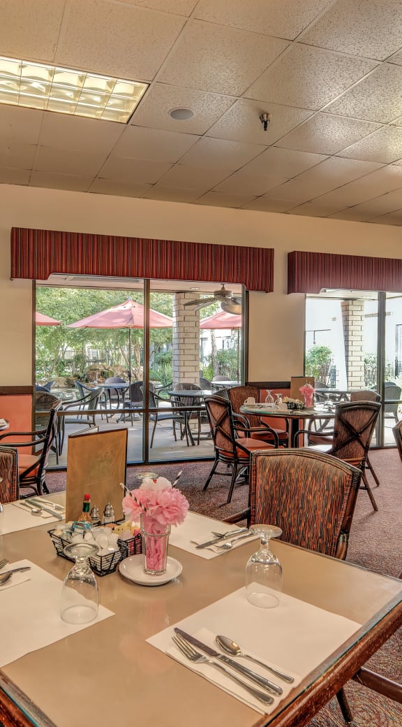 a large dining room with tables and chairs and windows at Campus Commons Senior Living, Sacramento