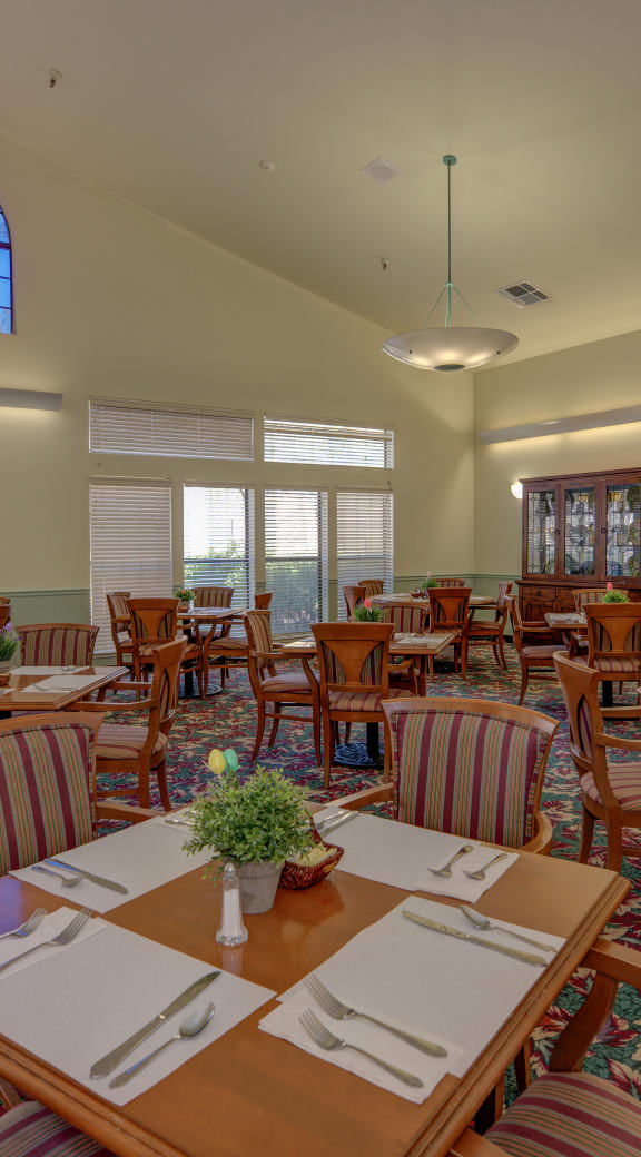 a large dining room with tables and chairs and windows at Hilltop Commons Senior Living, Grass Valley, 95945