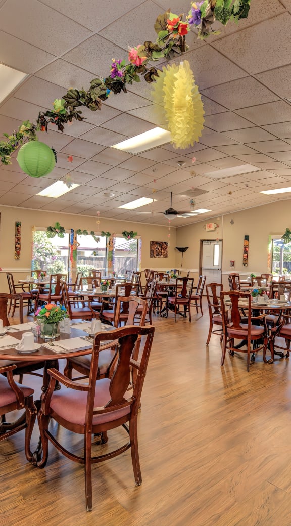 a large dining room with tables and chairs and windows at Lodi Commons Senior Living, California, 95240