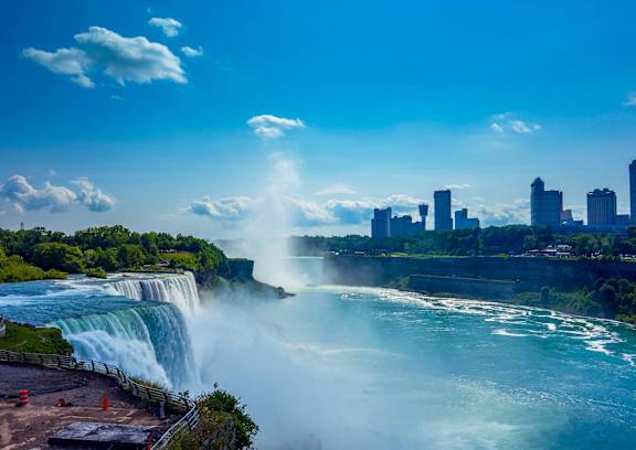 A large waterfall with a city skyline in the background.