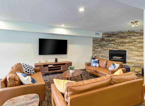 A living room with a stone fireplace and a flat screen TV mounted on the wall.