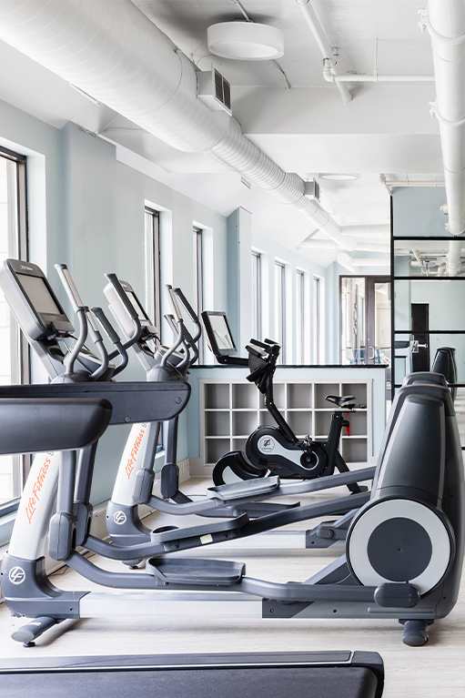 a workout room with treadmills and a tv