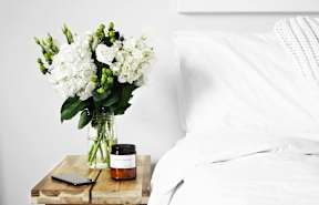 A white bed with a white pillow and a white blanket.