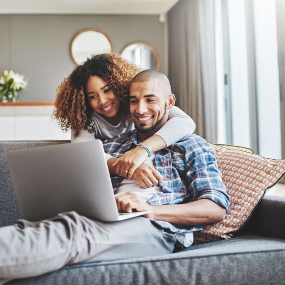 a man and woman sitting on a couch with a laptop at The Grove Brentwood in Nashville, TN