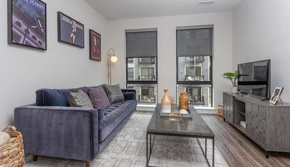 A living room with a grey couch, a coffee table, and a television. at Coda at Bryant Street, Washington, DC 20002