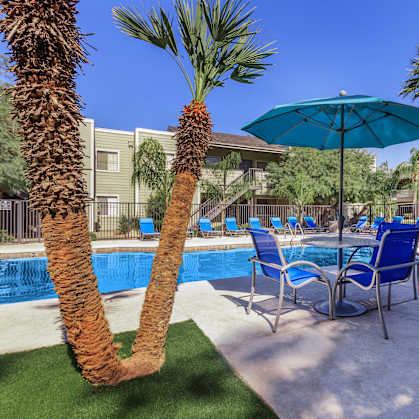 A pool area with a blue umbrella and chairs.
