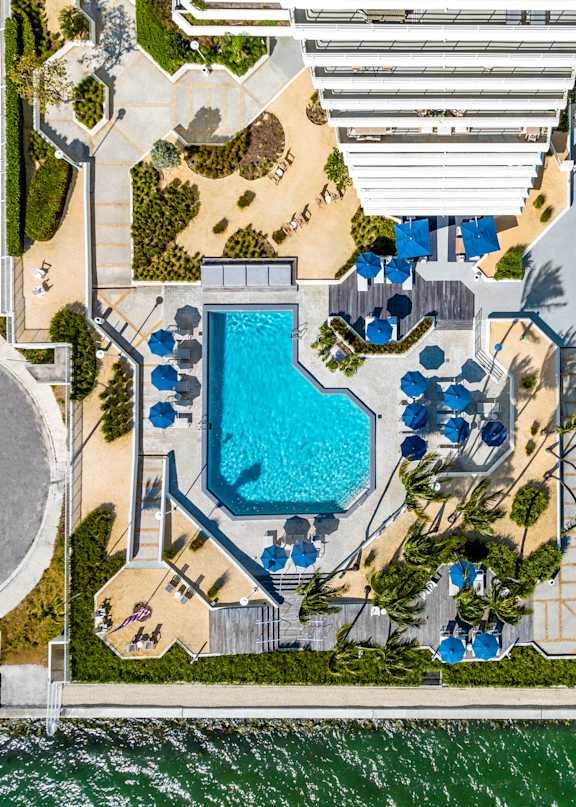 A wooden deck with white chairs and an umbrella overlooking a body of water. at The Hamilton, Miami, FL