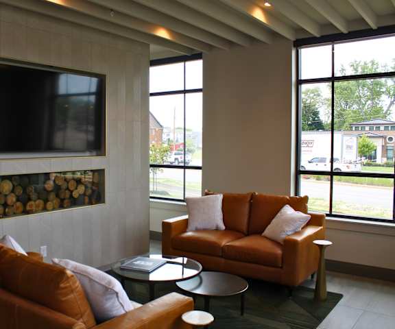 A living room with a brown couch and a television mounted on the wall.