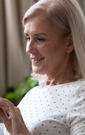 an older woman sitting in a chair looking at her cell phone