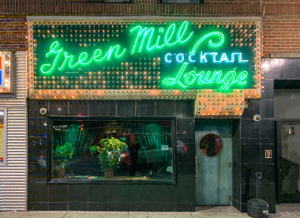 a neon sign in the window of green mill cocktail lounge