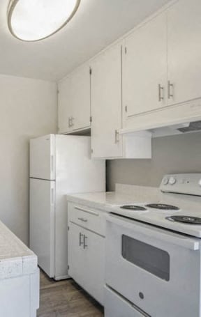 an empty kitchen with white cabinets and stainless steel appliancesat The Arches Apartments, LLC, El Cajon, CA