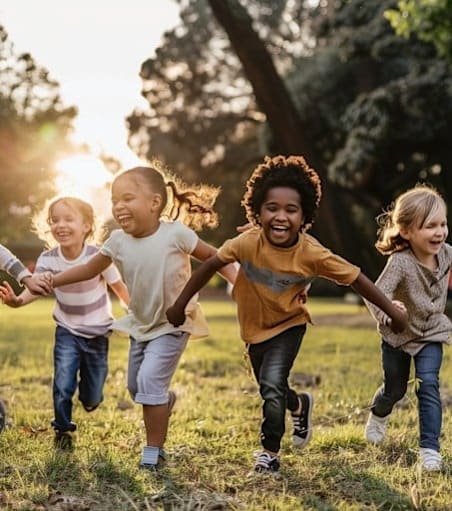 A group of children are running and holding hands in a field.