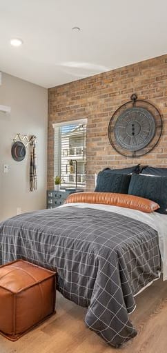 Bedroom with red brick accent wall and sliding glass doors leading to balcony.