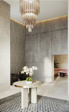 A chandelier hangs over a round table with a vase of white flowers on it.