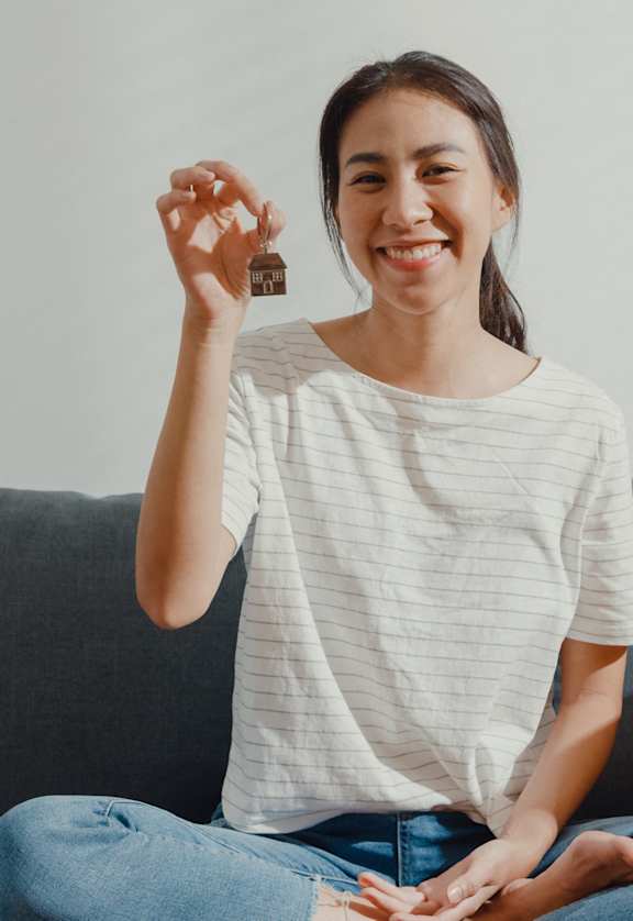A woman is sitting on a couch with a box labeled "Bedroom" in front of her.