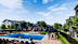 A pool area with people relaxing and a building in the background.
