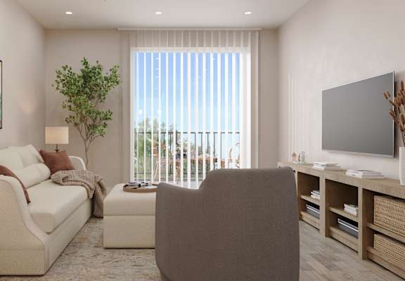A living room with a white couch, a chair, a lamp, a small tree, and a television.