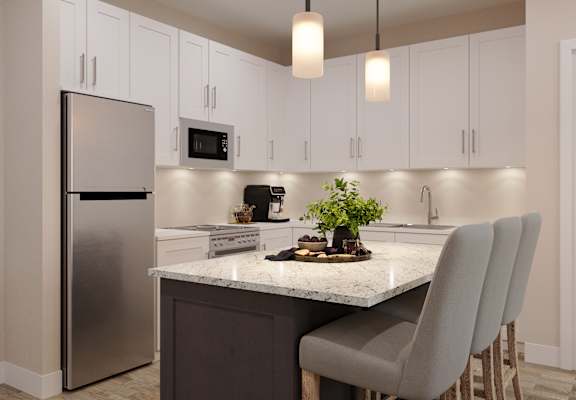 A kitchen with a refrigerator, microwave, and a counter with chairs.