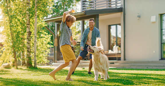 A man and a woman are playing with a dog in a yard at Walker Place Apartments, Texas, 76643
