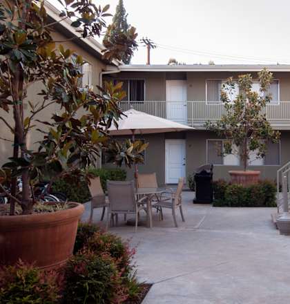 a patio with a table and chairs in front of a building