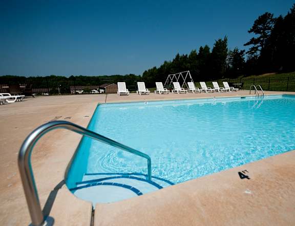 A pool with a ladder and chairs around it.