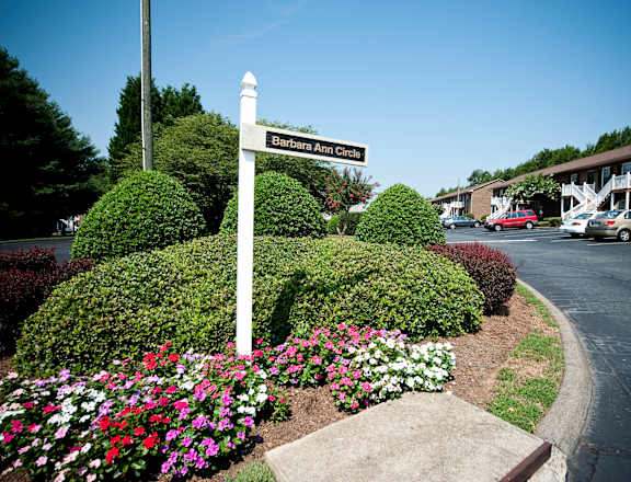A street sign for Barbara Ann Circle stands in front of a flower bed.