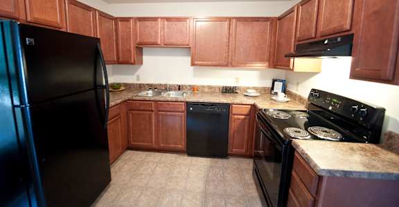 A kitchen with brown cabinets and black appliances.
