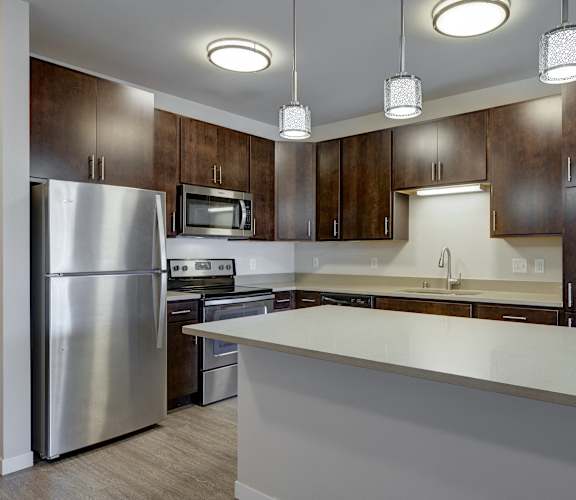 a kitchen with a white counter top and a stainless steel refrigerator at One Glenn Place, Fitchburg, WI, 53711