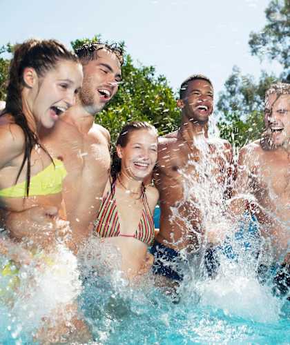 a group of people in a pool laughing and splashing in the water