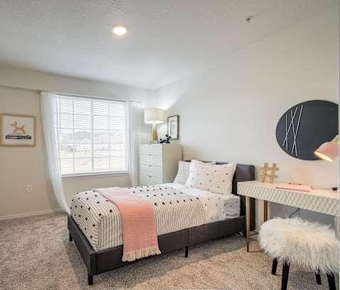 A bedroom with a bed, desk, and chair.