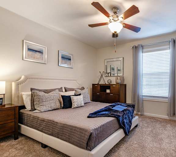 A bedroom with a bed, nightstand, and pictures on the wall.