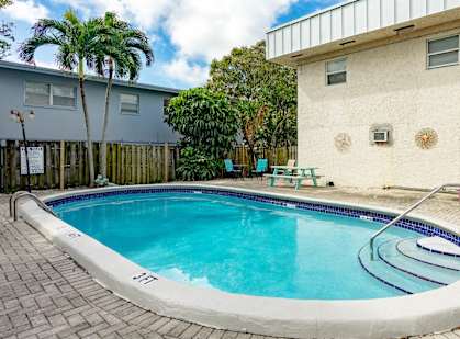 a swimming pool in front of a house with palm trees