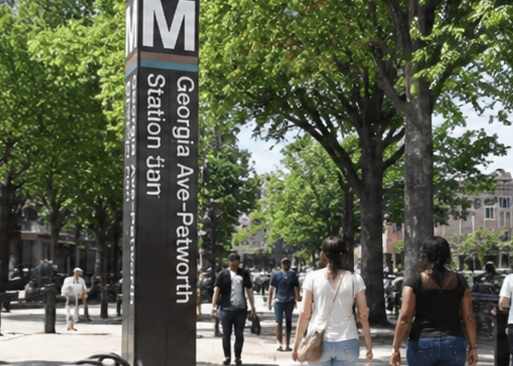 Two women walking past a sign for Georgia Ave-Petworth station.