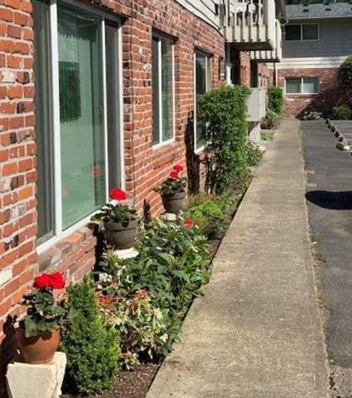 A red brick house with a flower bed in front.