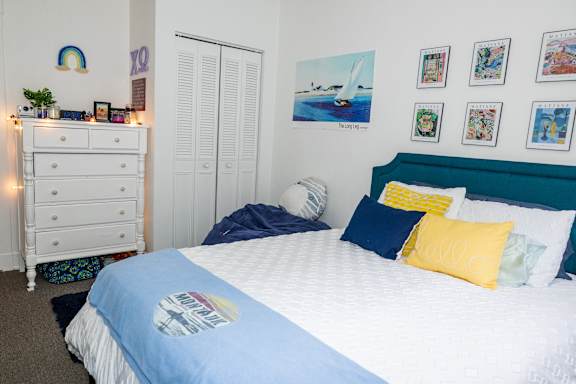A bedroom with a bed, dresser, and wall art.