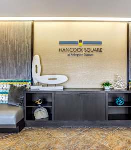 A Hancock Square at Arlington Station sign is on a wall above a shelf.